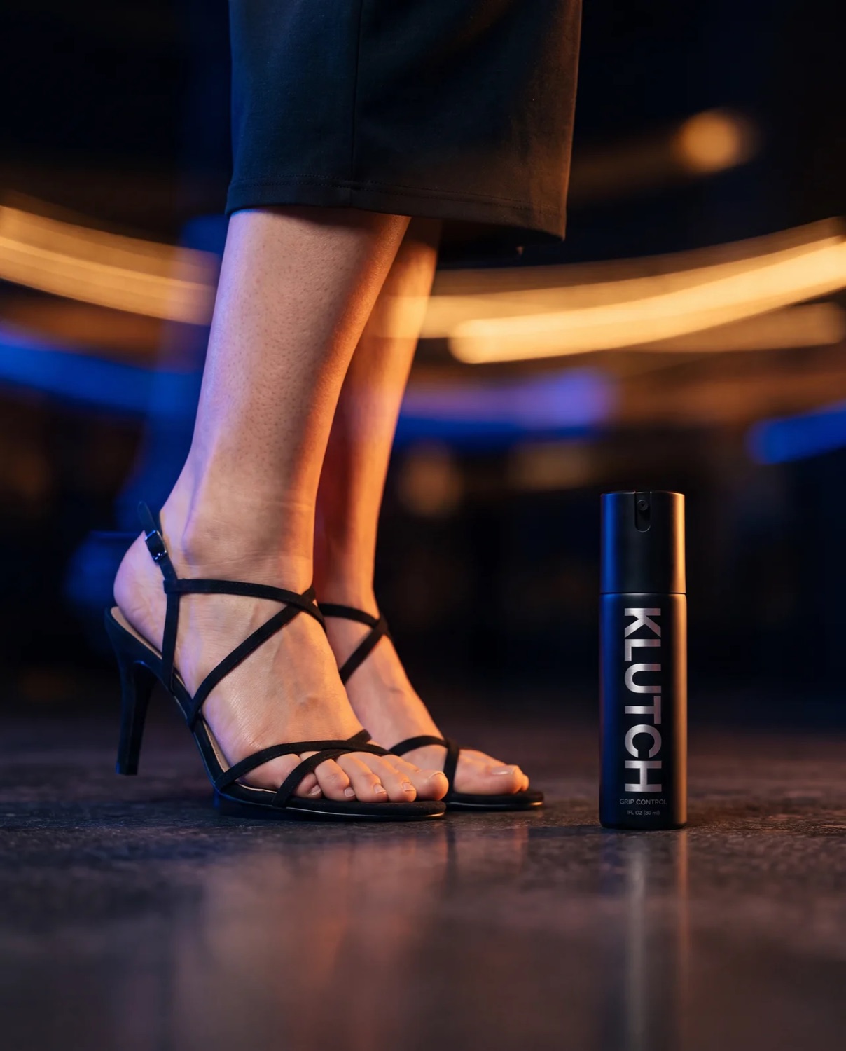Black strappy heels dancing beside the Klutch bottle