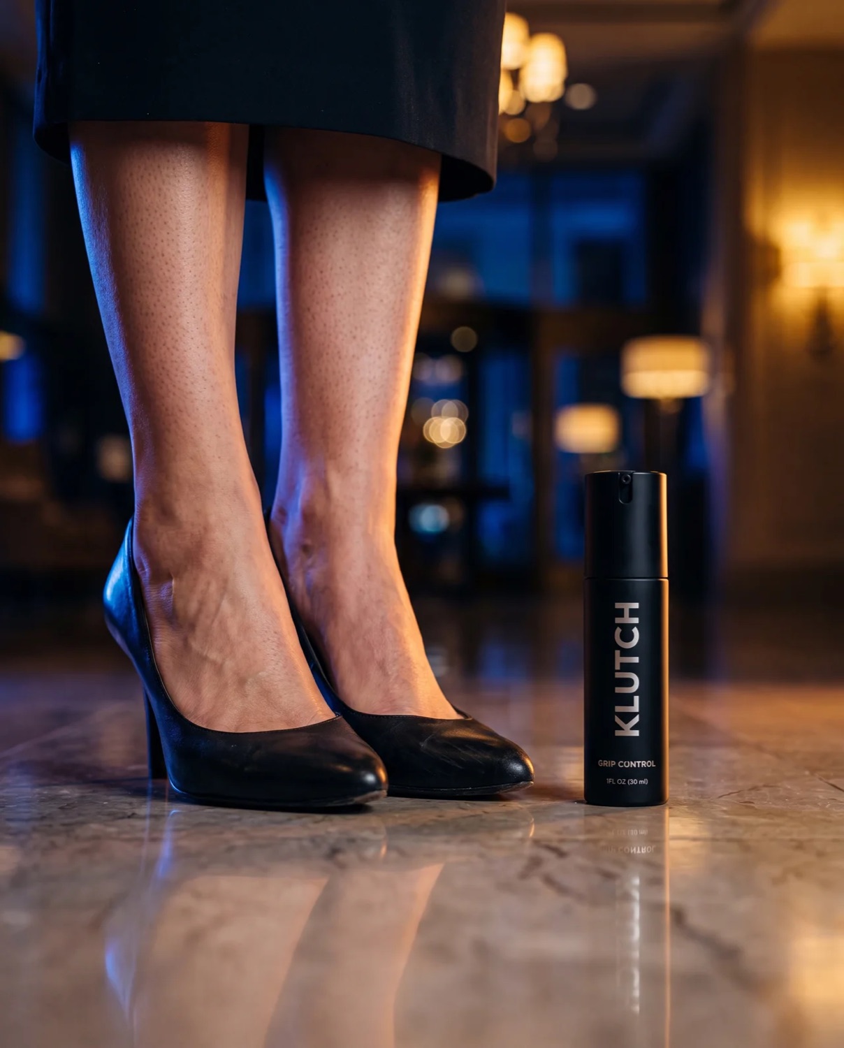 Black pumps on a lobby floor beside the Klutch bottle